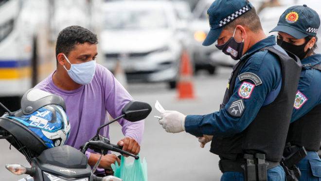 Policial militar faz inspeção de documentos de motoqueiro em Belém do Pará, durante vigência do lockdown que restringiu a circulação de pessoas nas ruas.