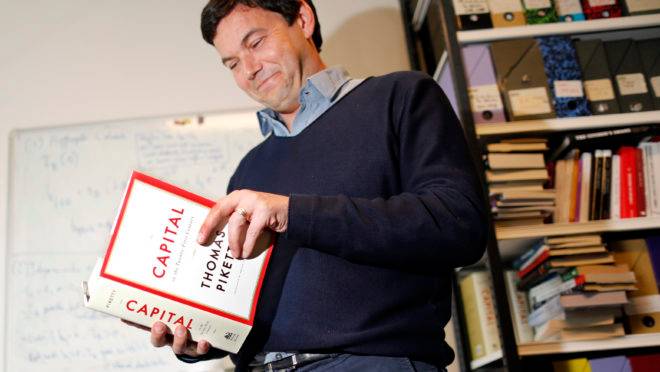 French economist and academic Thomas Piketty, poses in his book-lined office at the French School for Advanced Studies in the Social Sciences (EHESS), in Paris May 12, 2014. The 43-year-old Piketty’s book “Capital in the Twenty-First Century” has attracted praise and invective alike on its way to the top of the Amazon.com books best-seller list. Picture taken May 12, 2014. REUTERS/Charles Platiau (FRANCE – Tags: POLITICS SOCIETY BUSINESS EDUCATION) – RTR3OZ0F