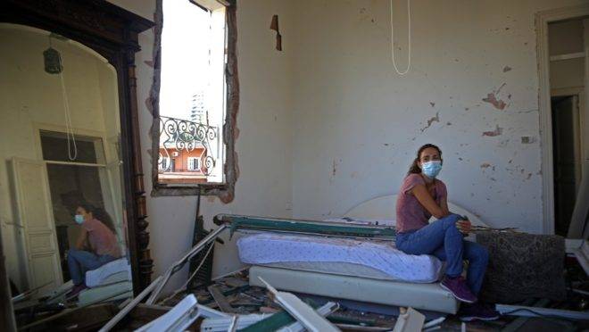 Em sua casa, mulher posa para foto em cômodo destruído pelas explosões em Beirute.
