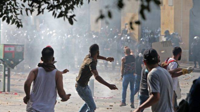 Manifestantes lançam pedras contra as forças de segurança do Líbano durante confrontos no centro de Beirute, neste sábado (8).