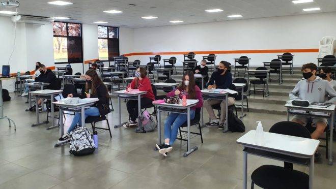 Imagem mostra sala de aula de colégio particular em Foz do Iguaçu com poucos alunos usando máscara e em distanciamento social, dentro do protocolo sanitário contra a disseminação do coronavírus.