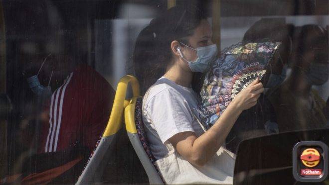 Uma passageira vestindo uma máscara usa um leque para se aliviar do calor em um ônibus de Berlim, em 15 de agosto de 2020.