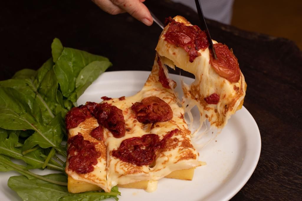 Polenta de queijo com tomate seco e rúcula. Foto: Alexandre Carnieri/Divulgação Polenta de queijo com tomate seco e rúcula. Foto: Alexandre Carnieri/Divulgação