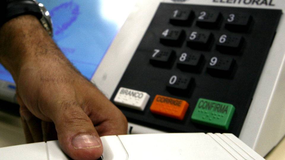 Cota racial estreia nas eleições de 2020 sob risco de candidatos laranjas. Entenda Mão de eleitor faz biometria com a urna eletrônica ao fundo.
