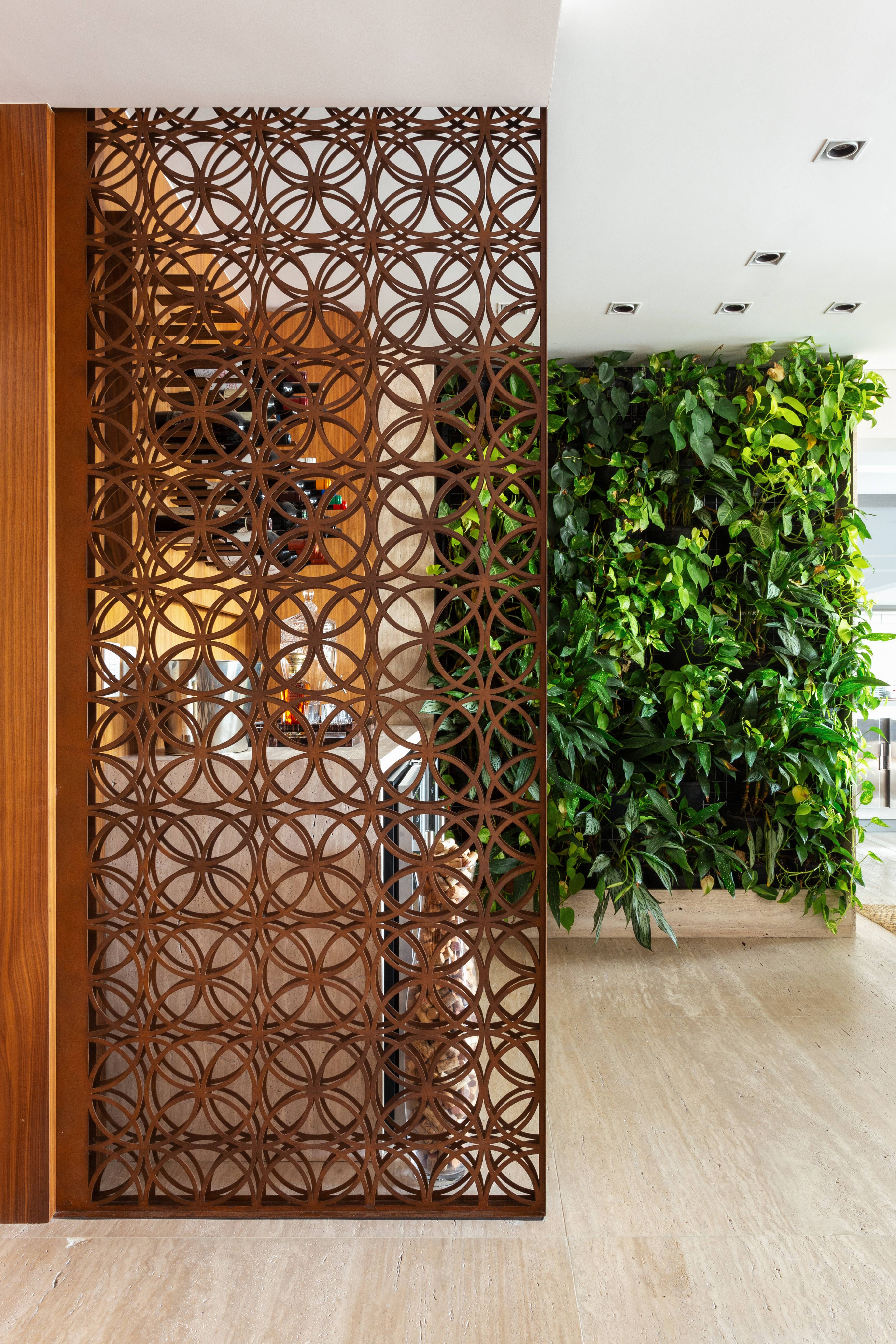 A divisória vazada feita em aço foi inserida pela Dantas & Passos Arquitetura para delimitar a entrada para uma adega A divisória vazada feita em aço foi inserida pela Dantas & Passos Arquitetura para delimitar a entrada para uma adega