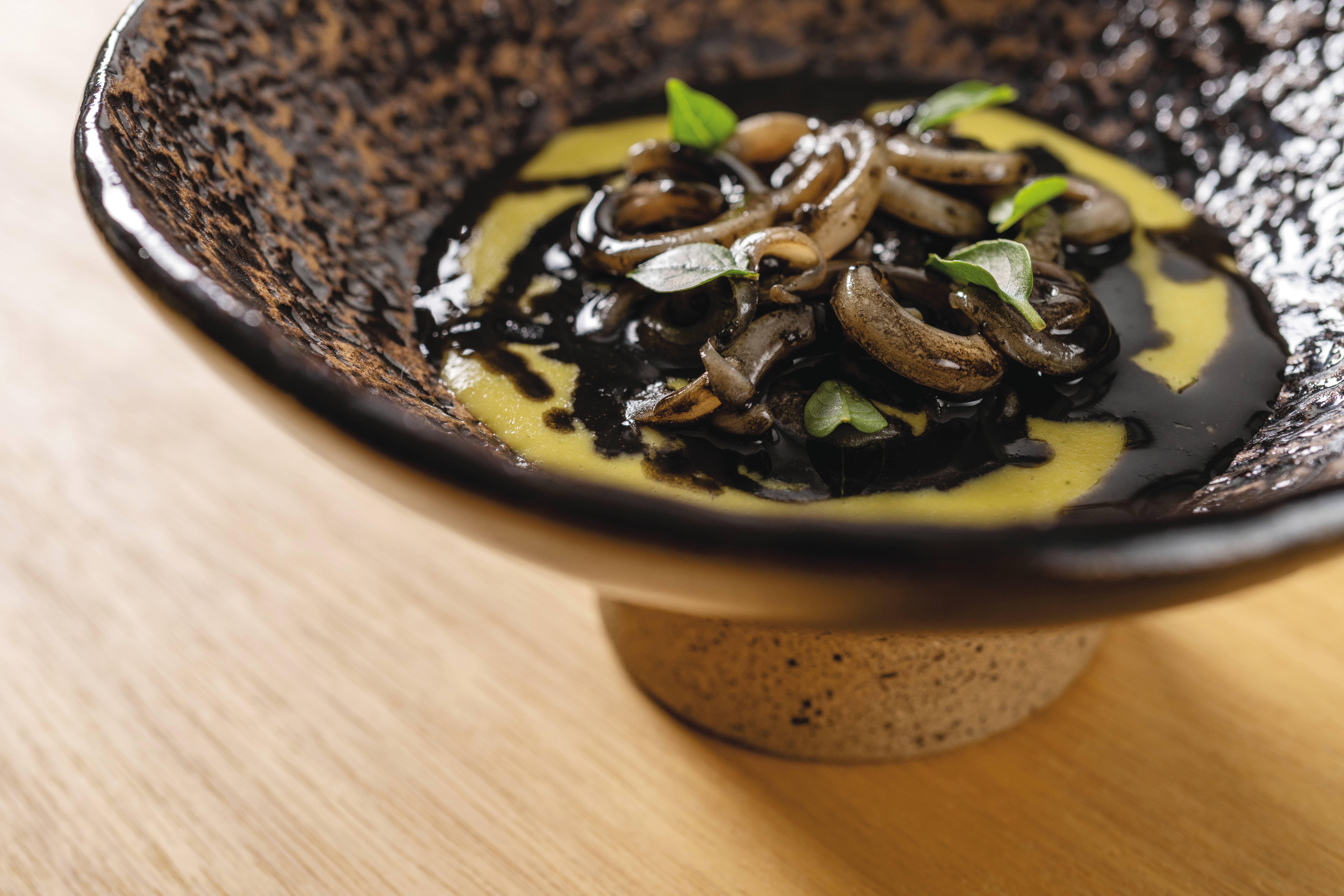 No novo menu, Do Campo ao Mar, combinações surpreendentes como o milho verde assado e cozido com capim-limão, servido com lula e salsa negra de frutos do mar. Foto: Rubens Kato/Manu No novo menu, Do Campo ao Mar, combinações surpreendentes como o milho verde assado e cozido com capim-limão, servido com lula e salsa negra de frutos do mar. Foto: Rubens Kato/Manu