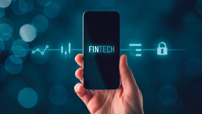Fintech (financial technology) on smart phone concept. Hand with smart phone and text fintech and financial icons.