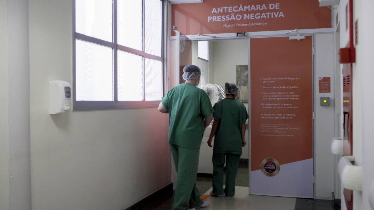 A imagem ilustra uma das ações tomadas pelo Hospital Marcelino Champagnat para lidar com a pandemia. Ela mostra profissionais da saúde entrando na antecâmara de pressão negativa, que filtra o ar e impede a contaminação de outras áreas do hospital. A imagem ilustra uma das ações tomadas pelo Hospital Marcelino Champagnat para lidar com a pandemia. Ela mostra profissionais da saúde entrando na antecâmara de pressão negativa, que filtra o ar e impede a contaminação de outras áreas do hospital.