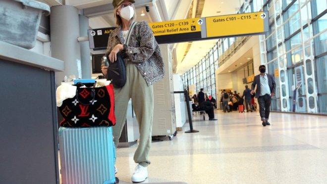 De máscara, mulher espera por voo em aeroporto de New Jersey, nos EUA.