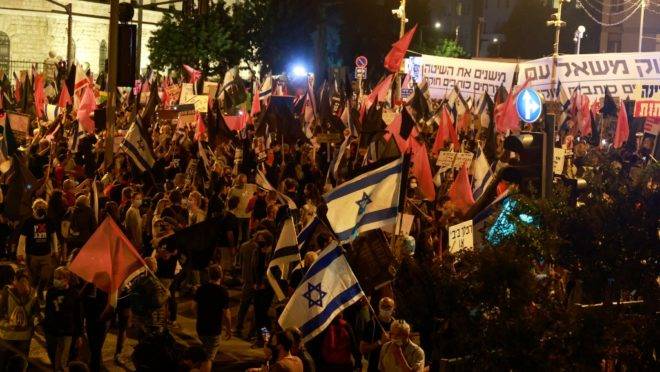 Manifestantes agitam bandeiras durante uma manifestação perto da residência do primeiro-ministro israelense Benjamin Netanyahu em Jerusalém, em 31 de outubro de 2020, para exigir sua renúncia por causa de seus casos de corrupção.