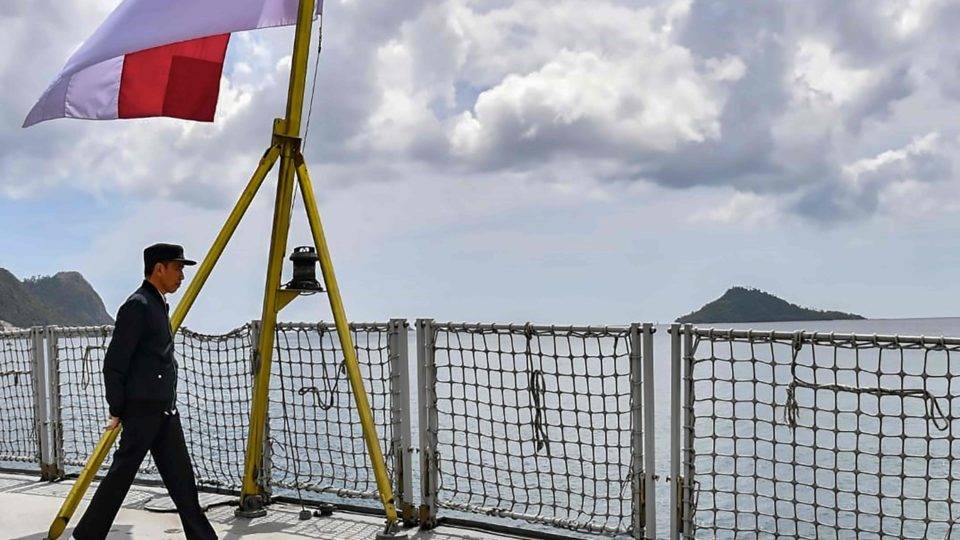 O presidente da Indonésia, Joko Widodo, passando pela bandeira do país em um navio da marinha
