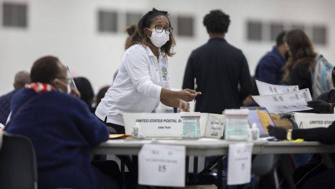 Um trabalhador do Departamento de Eleições de Detroit pede uma cédula por correio no Conselho de Contagem Central no Centro TCF em 4 de novembro de 2020 em Detroit, Michigan.