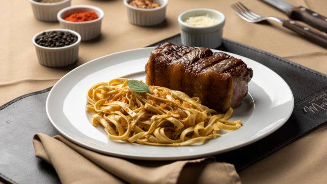 Bife de chorizo com tagliatelle na manteiga e lâminas de alho crocante, opção do jantar do Cabaña Montefusco Parrilla Argentina.
