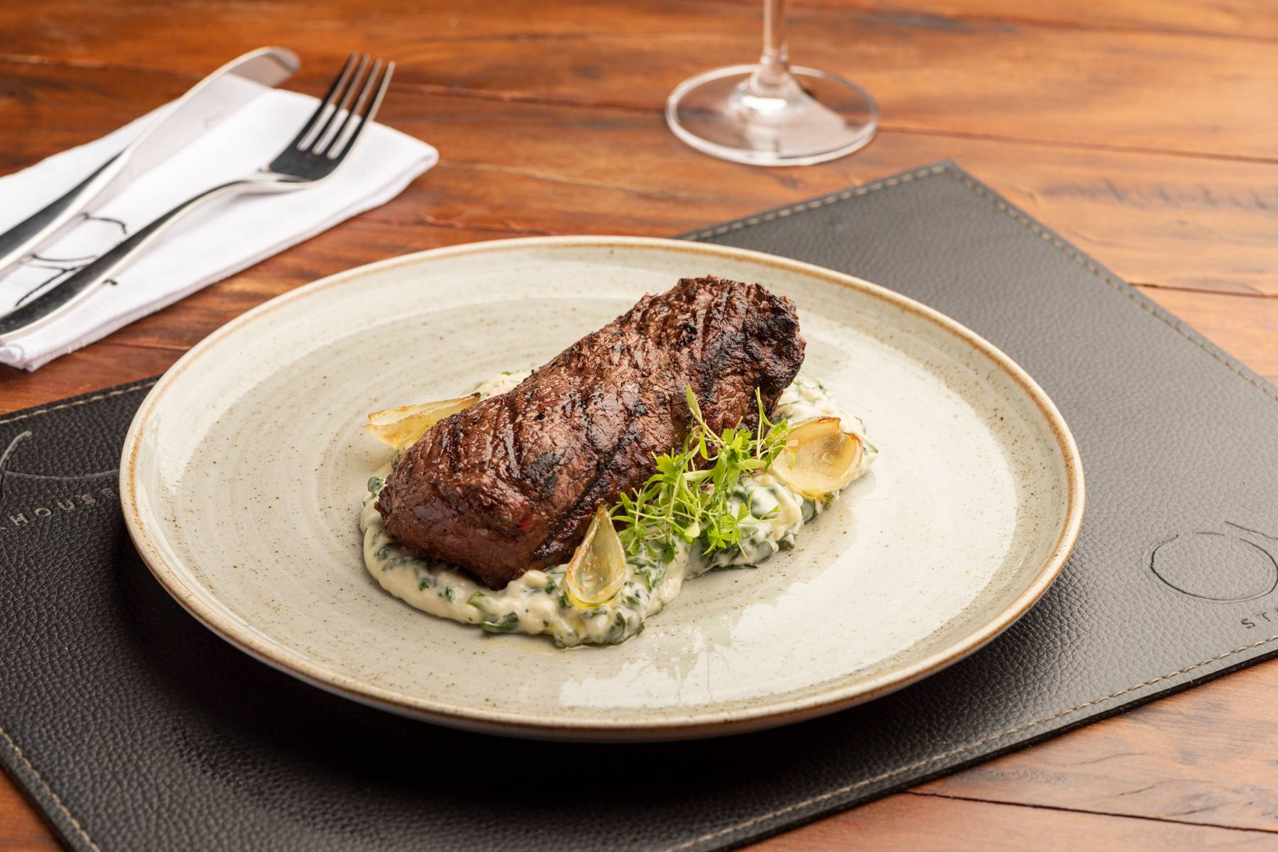 Top sirloin, corte alto de Angus, servido ao ponto da casa, com creme de alcachofras, parmesão, espinafre e chalotas caramelizadas na brasa, opção da Ox Room Steakhouse. Top sirloin, corte alto de Angus, servido ao ponto da casa, com creme de alcachofras, parmesão, espinafre e chalotas caramelizadas na brasa, opção da Ox Room Steakhouse.