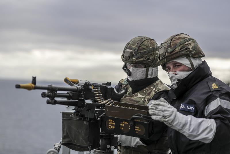 Um artilheiro e instrutor a bordo do HMS Albion manipulando uma arma durante o exercício militar Joint Warrior, em 2019