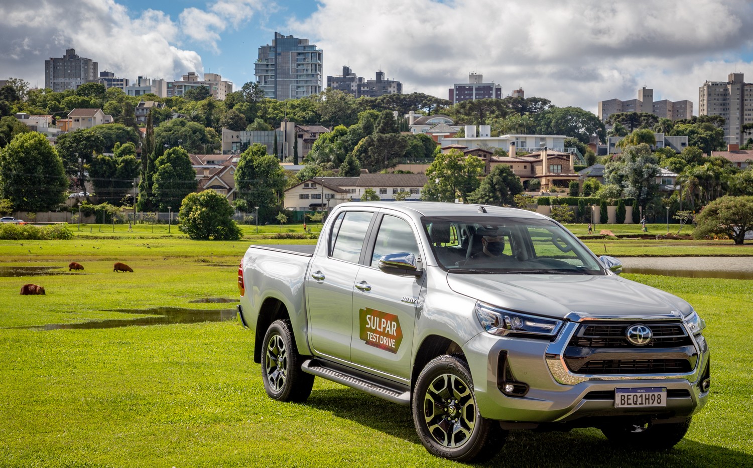 Toyota Hilux no Parque Barigui, em Curitiba, com capivaras ao fundo.
