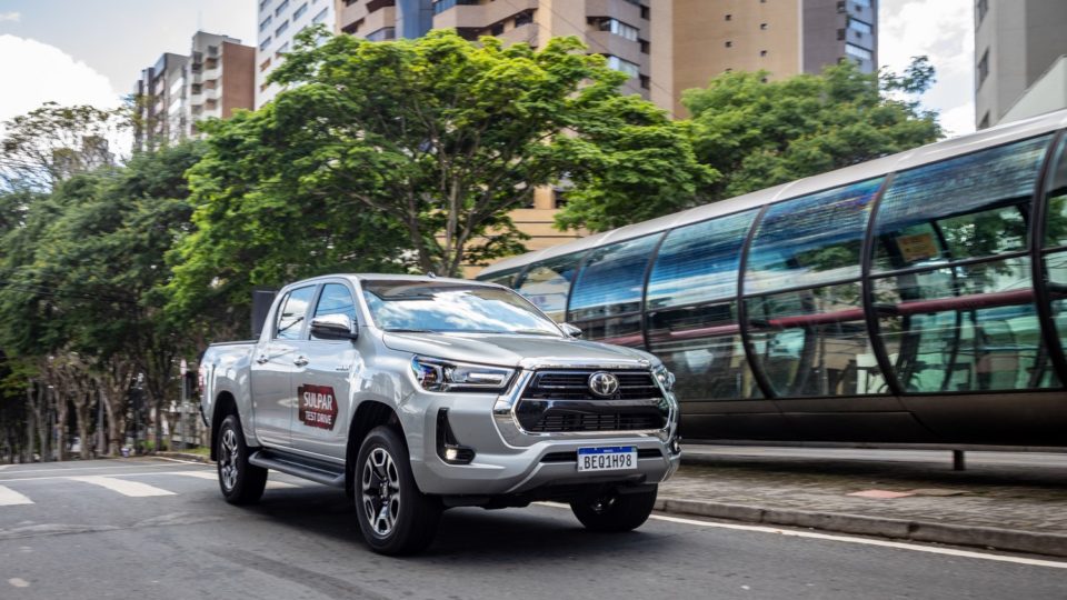 Toyota Hilux pelas ruas de Curitiba, com um tubo do expresso ao fundo