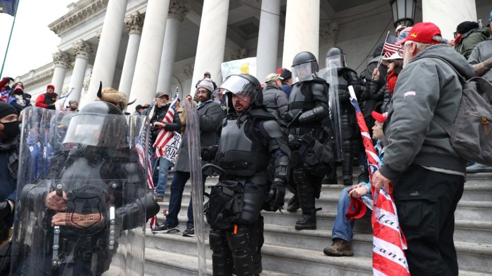 Após protestos violentos, Washington decreta toque de recolher por 12 horas Policiais do Capitólio com equipamentos anti-motim atravessam os manifestantes que estão reunidos no edifício do Capitólio dos EUA em 6 de janeiro de 2021 em Washington, DC. Imagem ilustrativa.
