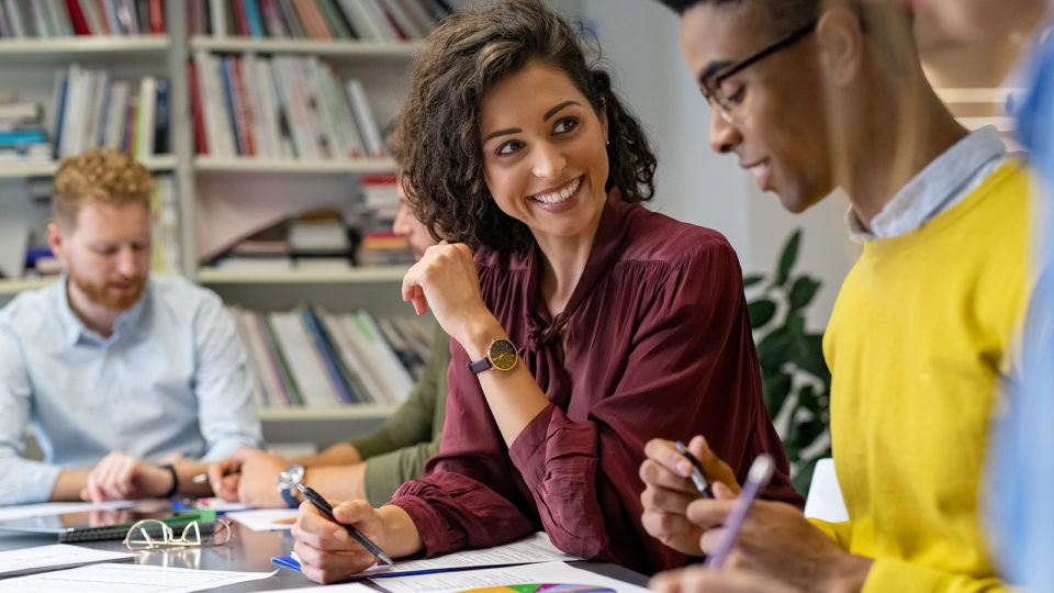 Grandes equipes são formadas por indivíduos com personalidades complementares Multiethnic business people discussing together their strategy. Happy businesswoman showing marketing strategy african businessman. Creative business team talking and smiling during brainstorming.