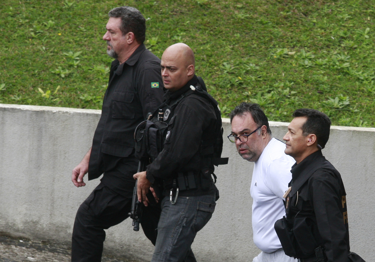 Ex-deputado André Vargas (de branco) durante transferência de presos da Lava Jato, em 2015: seis anos de prisão preventiva.