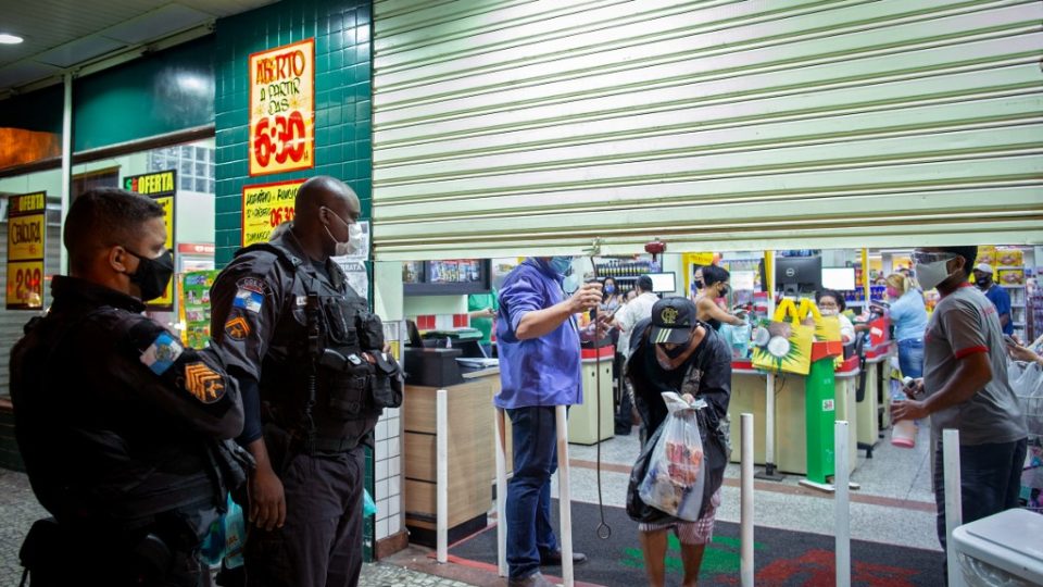 O vírus noturno Policiais militares ficam do lado de fora de um supermercado enquanto seu gerente fecha durante uma operação no bairro da Lapa, no Rio de Janeiro, Brasil, em 6 de março de 2021.