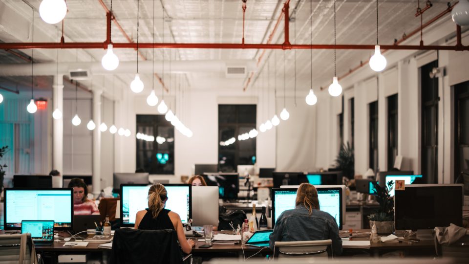 Espaços de conforto e modelo híbrido: as mudanças na arquitetura corporativa pós-pandemia Pessoas trabalhando em um escritório.