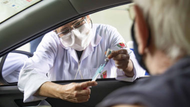 Agente de saúde prepara vacina para aplicar em idoso