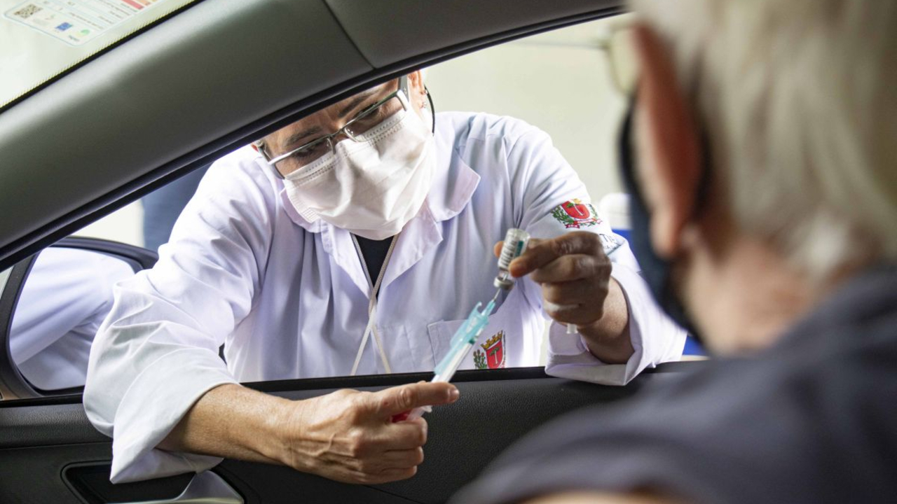 Agente de saúde prepara vacina para aplicar em idoso