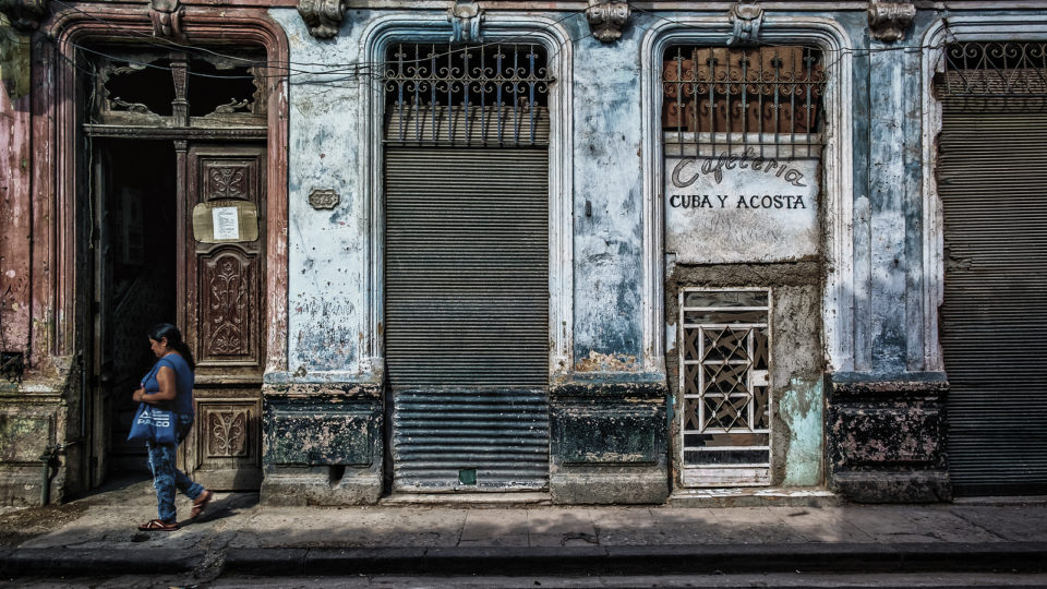 Não é só o embargo: os erros econômicos que condenaram Cuba à pobreza Mulher passa em frente de cafeteria fechada em Havana, Cuba