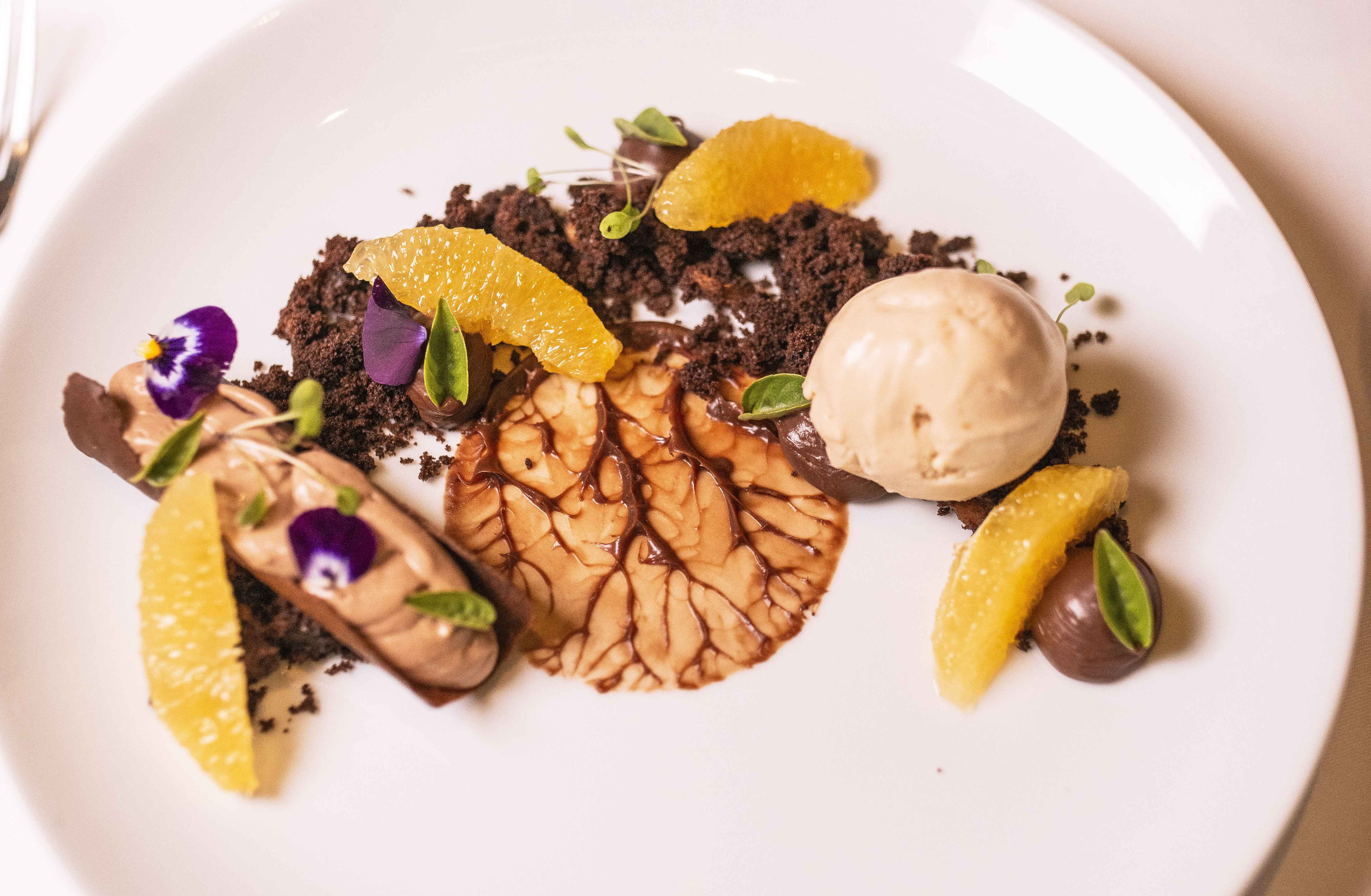 Canolli com creme legeré de cognac, farofa de cacau e castanha de caju, servido com ganache de chocolate ao leite e laranja e sorvete de castanha, a sobremesa. Canolli com creme legeré de cognac, farofa de cacau e castanha de caju, servido com ganache de chocolate ao leite e laranja e sorvete de castanha, a sobremesa.