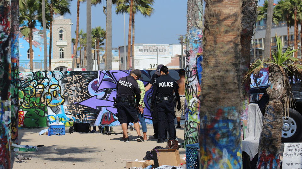 Como Venice Beach, em Los Angeles, virou epicentro de uma crise de sem-teto Polícia revista sem-teto em Venice Beach, Los Angeles. Praia se tornou o epicentro de uma crise de sem-tetos sem precedentes na região