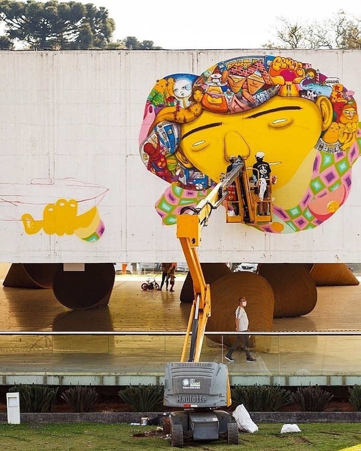 Registro de OSGÊMEOS grafitando a empena do MON. Registro de OSGÊMEOS grafitando a empena do MON.