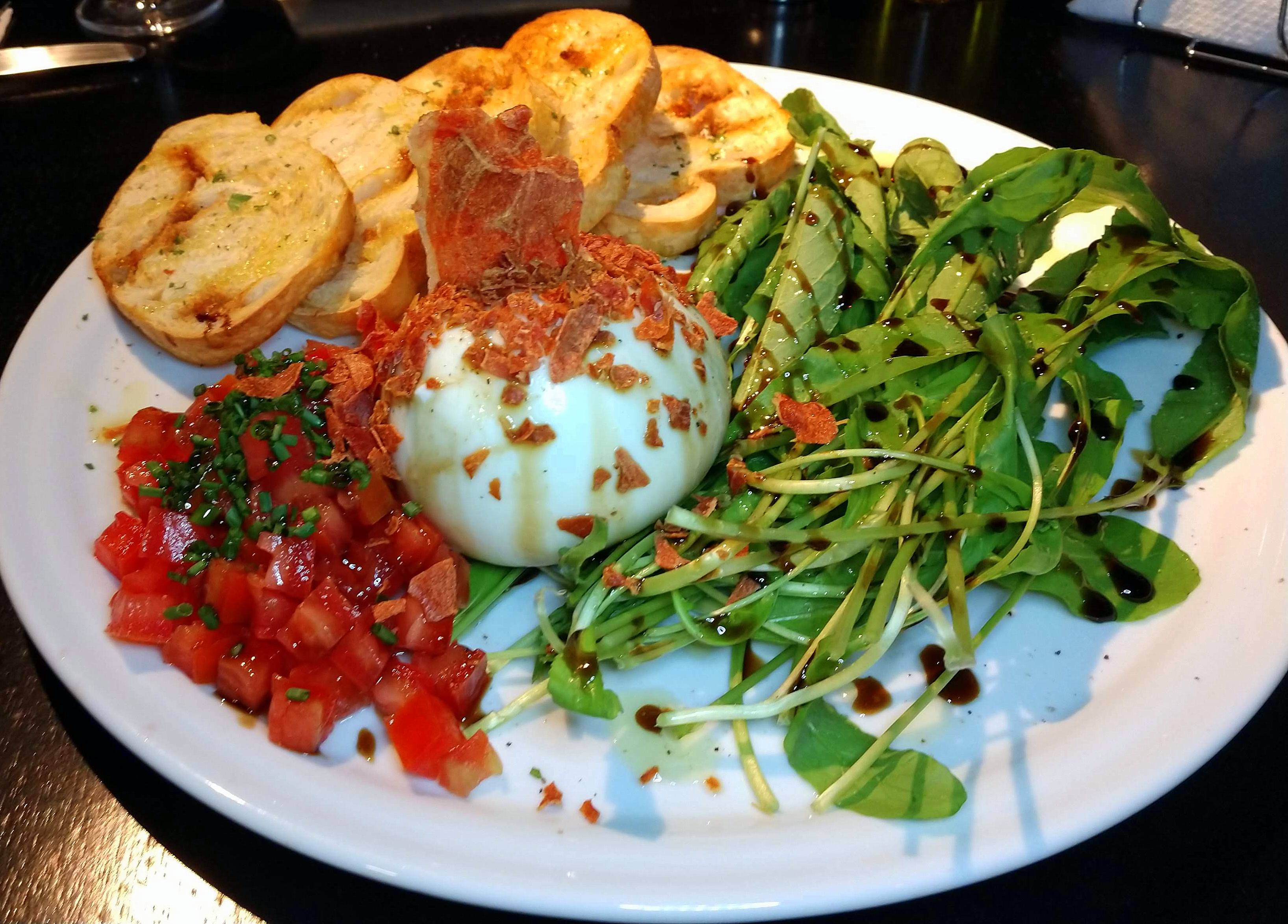 Burrata de búfala (com rúcula, presunto parma crispy, azeite de oliva, tomate, redução de aceto balsâmico e pão) - sugestão de entrada na Zahil. Burrata de búfala (com rúcula, presunto parma crispy, azeite de oliva, tomate, redução de aceto balsâmico e pão) - sugestão de entrada na Zahil.