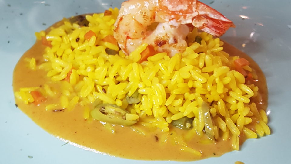 A harmoniosa combinação de sabores indianos, italianos e amazônicos do Curry Pasta Camarão grelhado com arroz pilaf aromático e curry de alho-poró e capim-limão (porção menu-degustação)