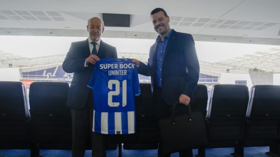 Representantes da Uninter e do FC Porto segurando uma camisa de futebol simbolizando a parceria entre organizações.