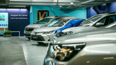 Loja física do V1, app de aluguel e assinatura de carros,mostrando carros à frente e logo ao fundo.