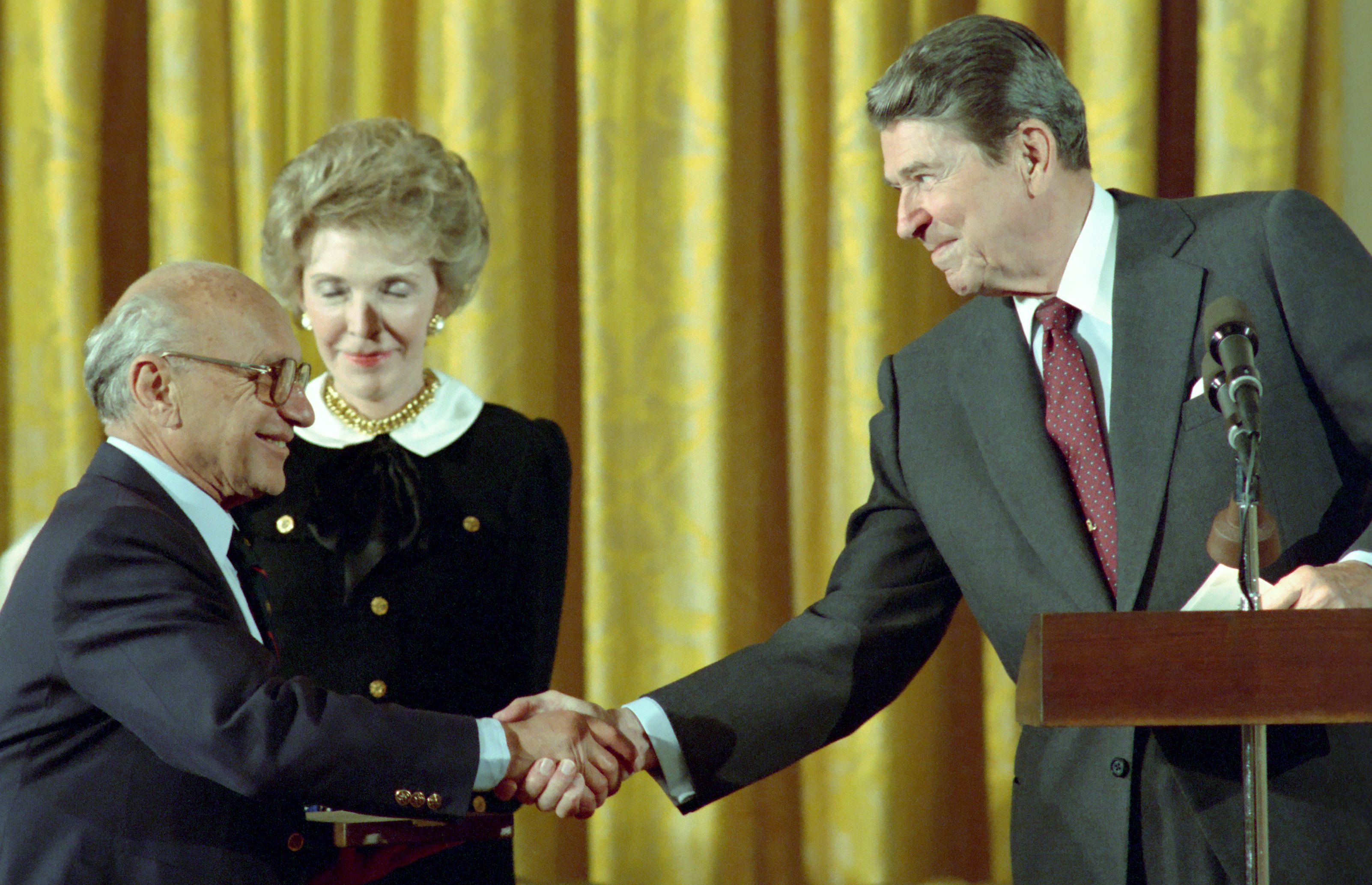 Milton Friedman recebendo a Medalha Presidencial da Liberdade das mãos de Ronald Reagan e sua esposa, Nancy Reagan, em 1988. Milton Friedman recebendo a Medalha Presidencial da Liberdade das mãos de Ronald Reagan e sua esposa, Nancy Reagan, em 1988.
