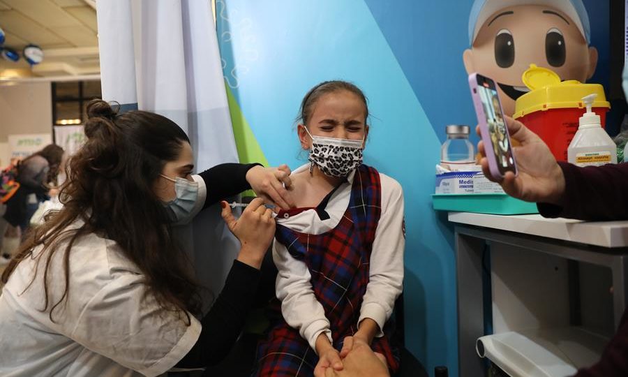 Anvisa autoriza vacinas para crianças. Qual é a mais segura: Pfizer ou Coronavac? Enfermeira aplica em uma criança dose da vacina contra a Covid-19 em Jerusalém, Israel, no dia 23 de novembro de 2021. Israel lançou uma campanha para oferecer a dose da vacina contra a Covid-19 para crianças entre cinco e 12 anos de idade