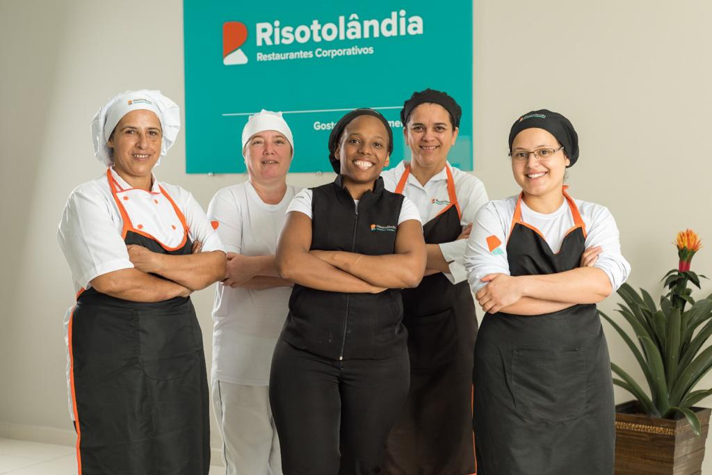 Cinco pessoas que fazem parte da equipe de alimentação do Grupo Risotolândia, devidamente uniformizadas