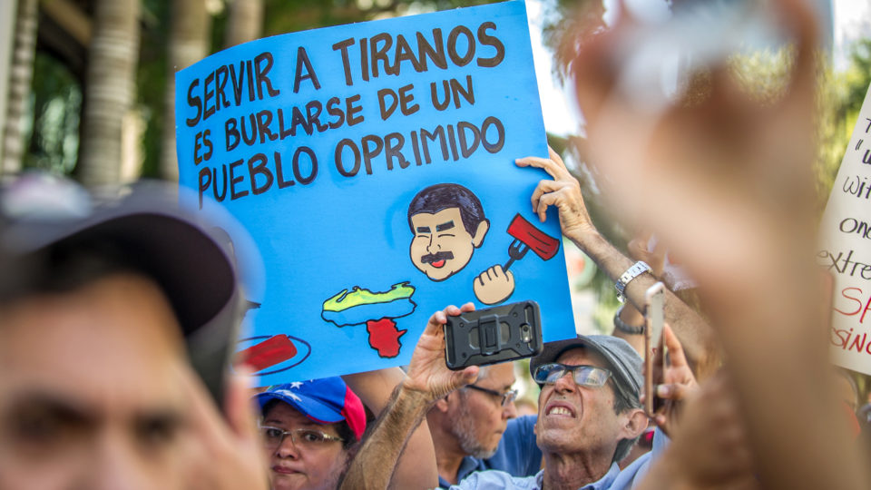 Mais uma tentativa de colocar um fim na ditadura venezuelana Manifestantes venezuelanos e cubanos protestam contra Nicolás Maduro em Miami, em 2018. No cartaz está escrito: “Servir a tiranos é zombar dos oprimidos”