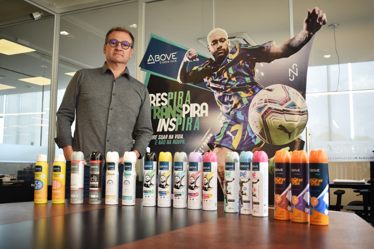 Gustavo Bacila, CEO da Baston, empresa por trás da marca Above, atrás de produtos da marca e a frente de um poster de Neymar Jr., embaixador da Above.