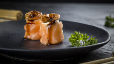Salmão, a estrela principal do criativo delivery do Taido Joe camarão flambado – arroz envolto por fatias de salmão coberto cream cheese finalizado com camarão maçaricado com molho tonkatsu, molho tarê, cebolinha e gergelim.