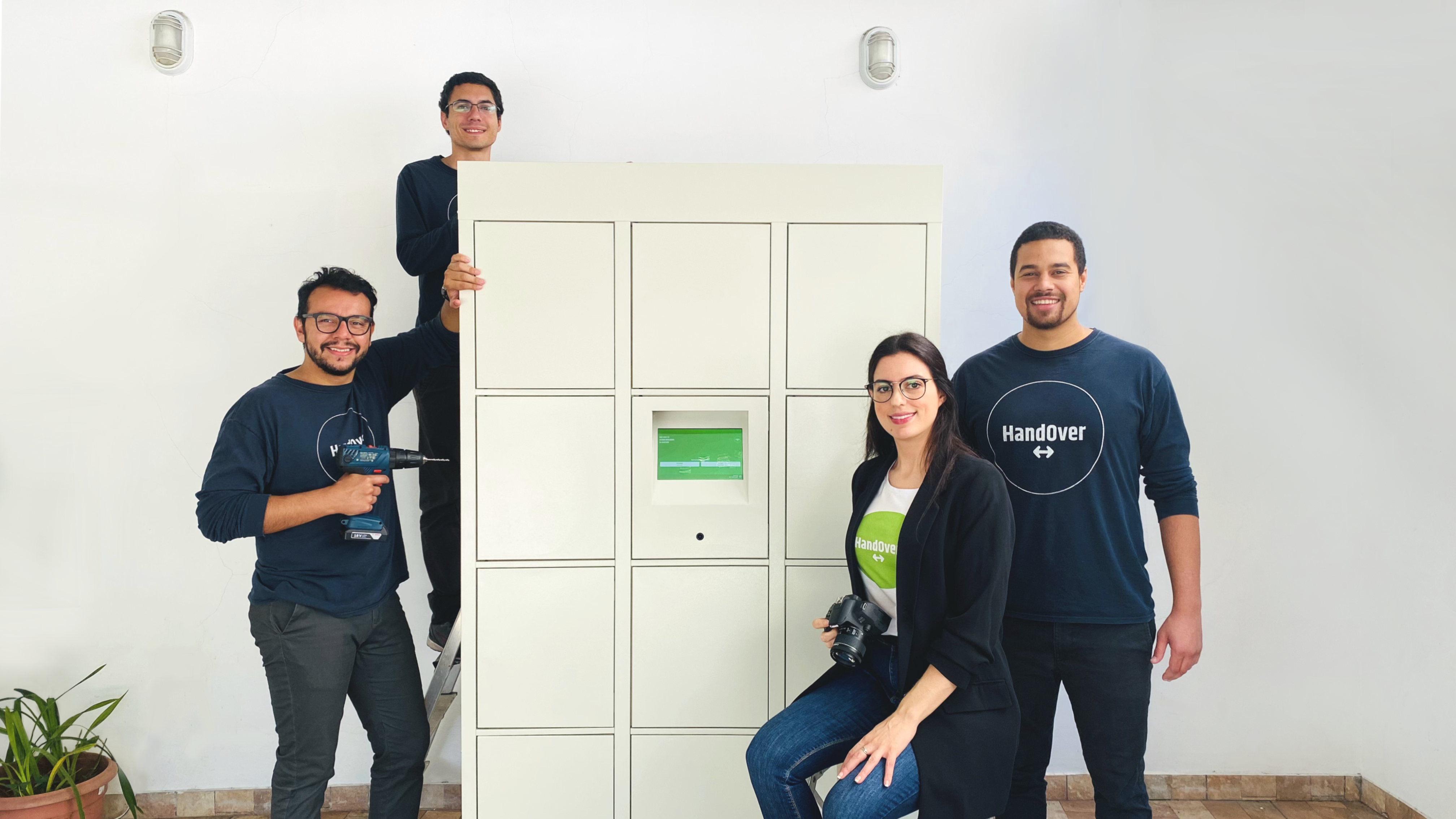 Membros da equipe da HandOver ao redor de um armário inteligente da empresa.