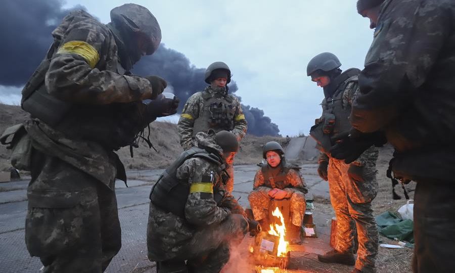 Soldados ucranianos se aquecem nas imediações de Kiev, neste domingo