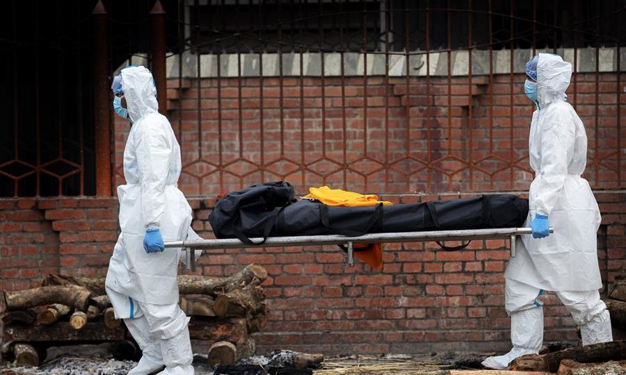 Quantas pessoas morreram por causa da pandemia? Mais do que as fontes oficiais afirmam Usando equipamentos de proteção individual (EPI), funcionários preparam piras funerárias para pessoas que morreram de complicações devido ao COVID-19, na margem do rio Bagmati, no templo Pashupati, em Katmandu, Nepal, 07 de maio de 2021.