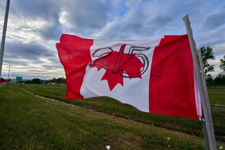 Uma bandeira canadense pendurada de cabeça para baixo, exibida como um protesto pelas supostas 215 crianças enterradas em uma vala comum sem identificação no terreno da antiga Kamloops Indian Residential School, na reserva Kahnawake, Canadá, 02 de julho de 2021.