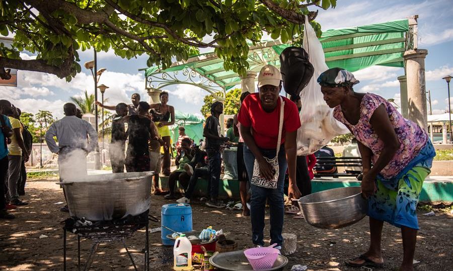 Haitianas cozinhando em uma praça, nesta semana, após fugir de confrontos de gangues