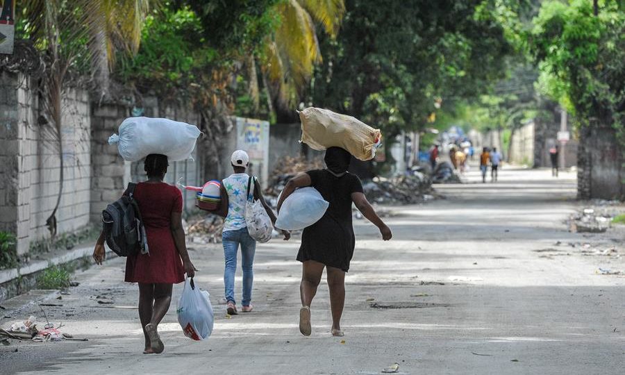Pessoas fogem de suas casas, carregando pertences em sacos