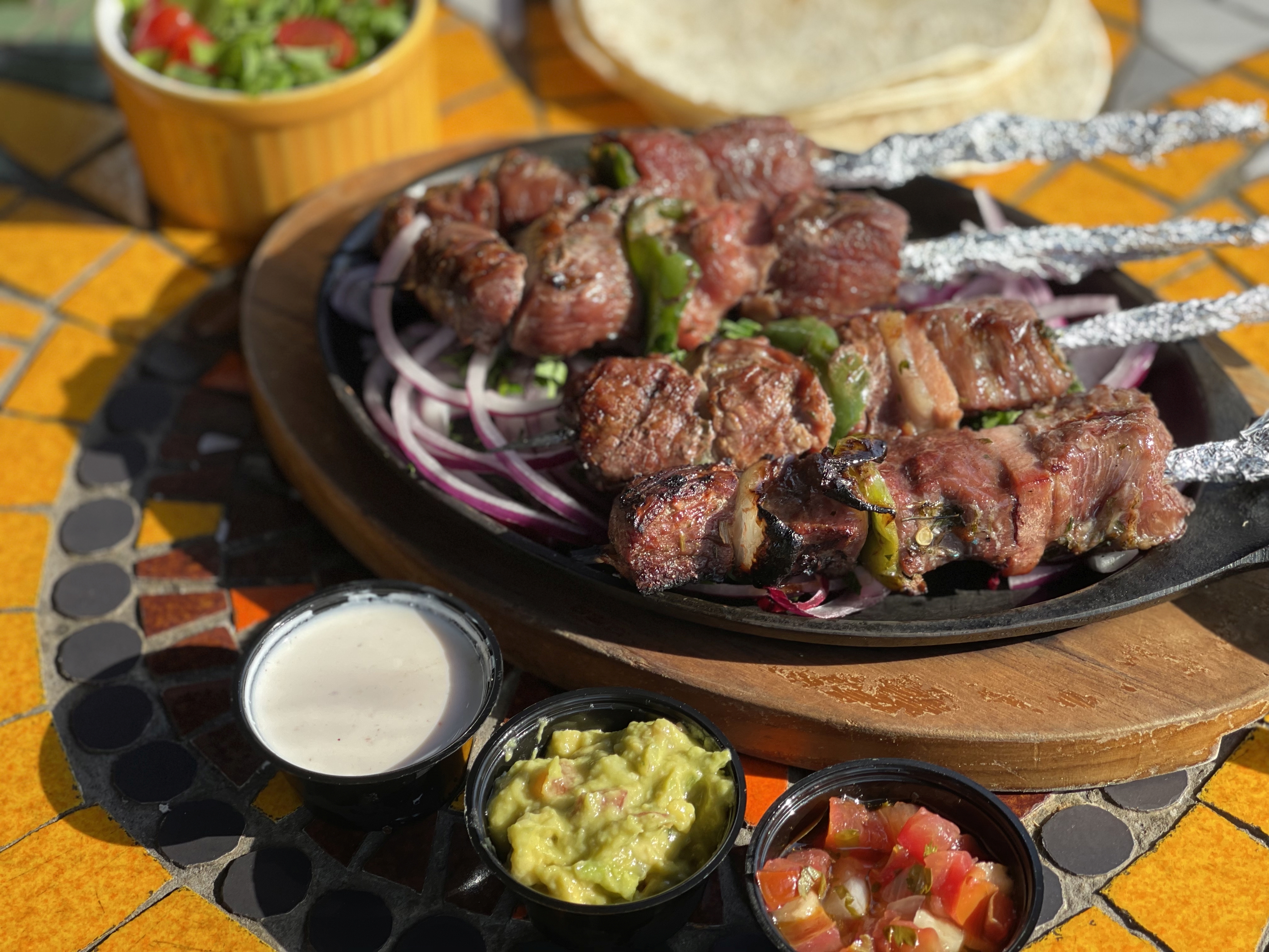Preparo do Talco El Pancho, os espetos são preparados com alcatra, cebola, tomates e pimentões, e acompanhados de guacamole, mini salada de rúcula, tortilhas de trigo e sour cream.