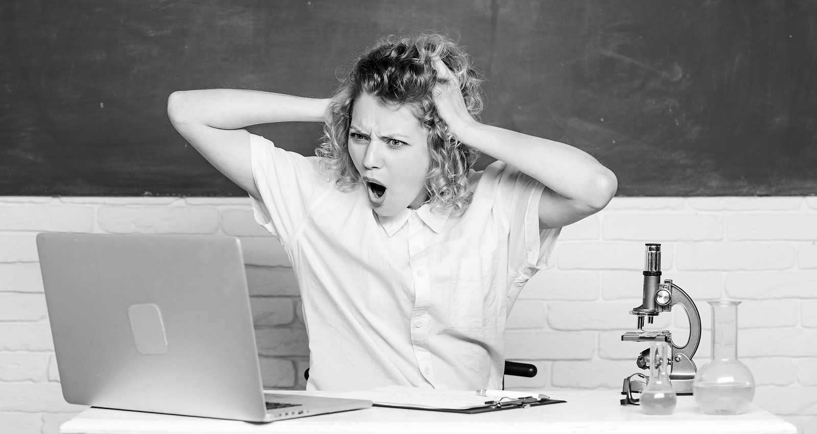 Estudante observa a tela do computador assustada e com indignação.